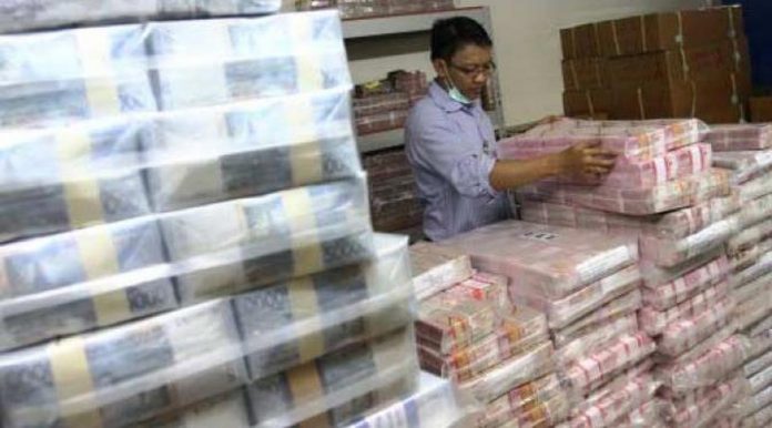 Petugas menata tumpukan uang rupiah.