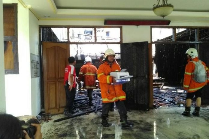 Petugas melakukan pembasahan di kantor Disperindag Jatim yang terbakar