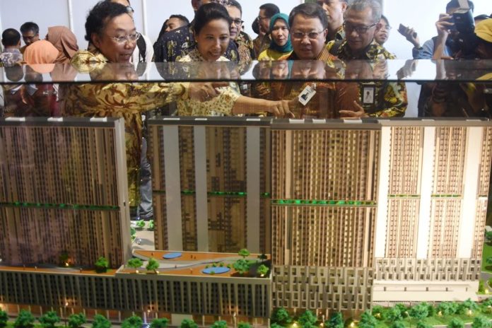 Menteri BUMN Rini Soemarno melihat maket proyek pembangunan rumah susun di Stasiun Pondok Cina, Depok, Jawa Barat, Senin (2/10). (