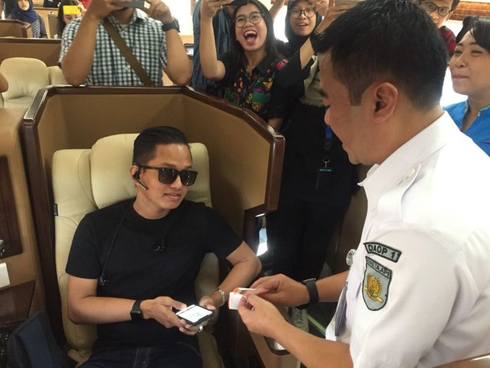 Dadan Rudiansyah membagikan suvenir dalam rangka Hari Pelanggan Nasional di Stasiun Gambir