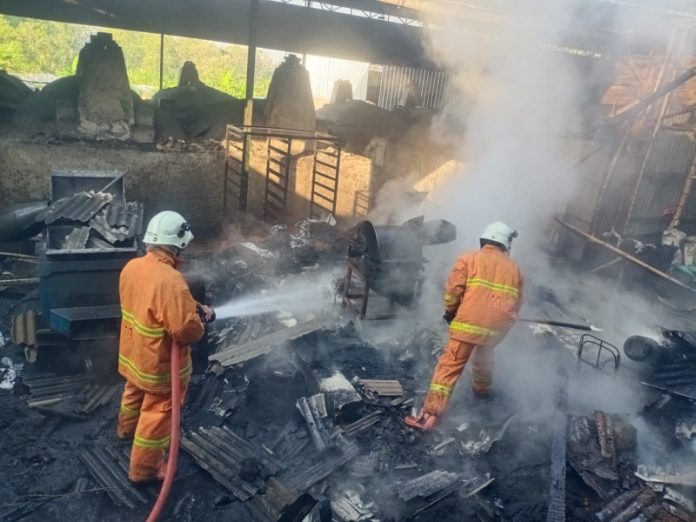 Petugas PMK saat memadamkan kebakaran di pabrik arang di Mojokerto, senin (29/5/2023) pagi.
