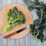 top-view-broccoli-with-knife-cutting-board-broccoli-leaves-wooden-background_141793-51909