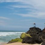 horizontal-shot-female-with-hat-blue-dress-rocky-beach_181624-46476