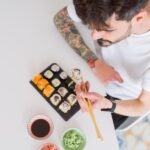 overhead-angle-young-man-eating-sushi-asian-food-using-choopsticks_839833-17872