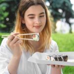 young-woman-eating-sushi-nature-maki-roll-closeup_169016-21080